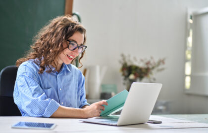 Young happy professional business woman online teacher or tutor sitting at work desk talking to student on video call teaching remote webinar or distance web meeting on laptop computer.